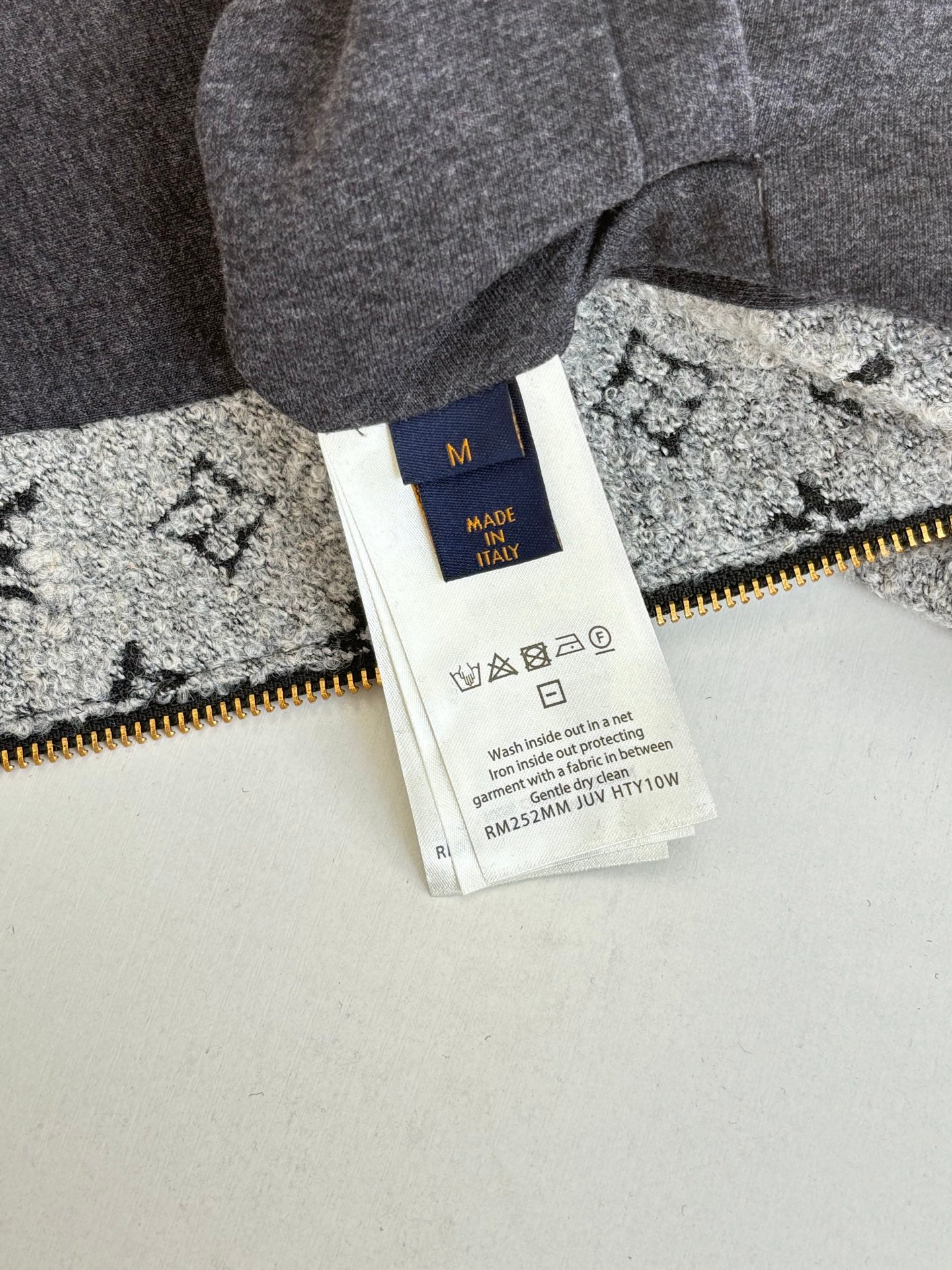 Long Louis Vuitton pants tag on gray fabric with yellow zipper and size label