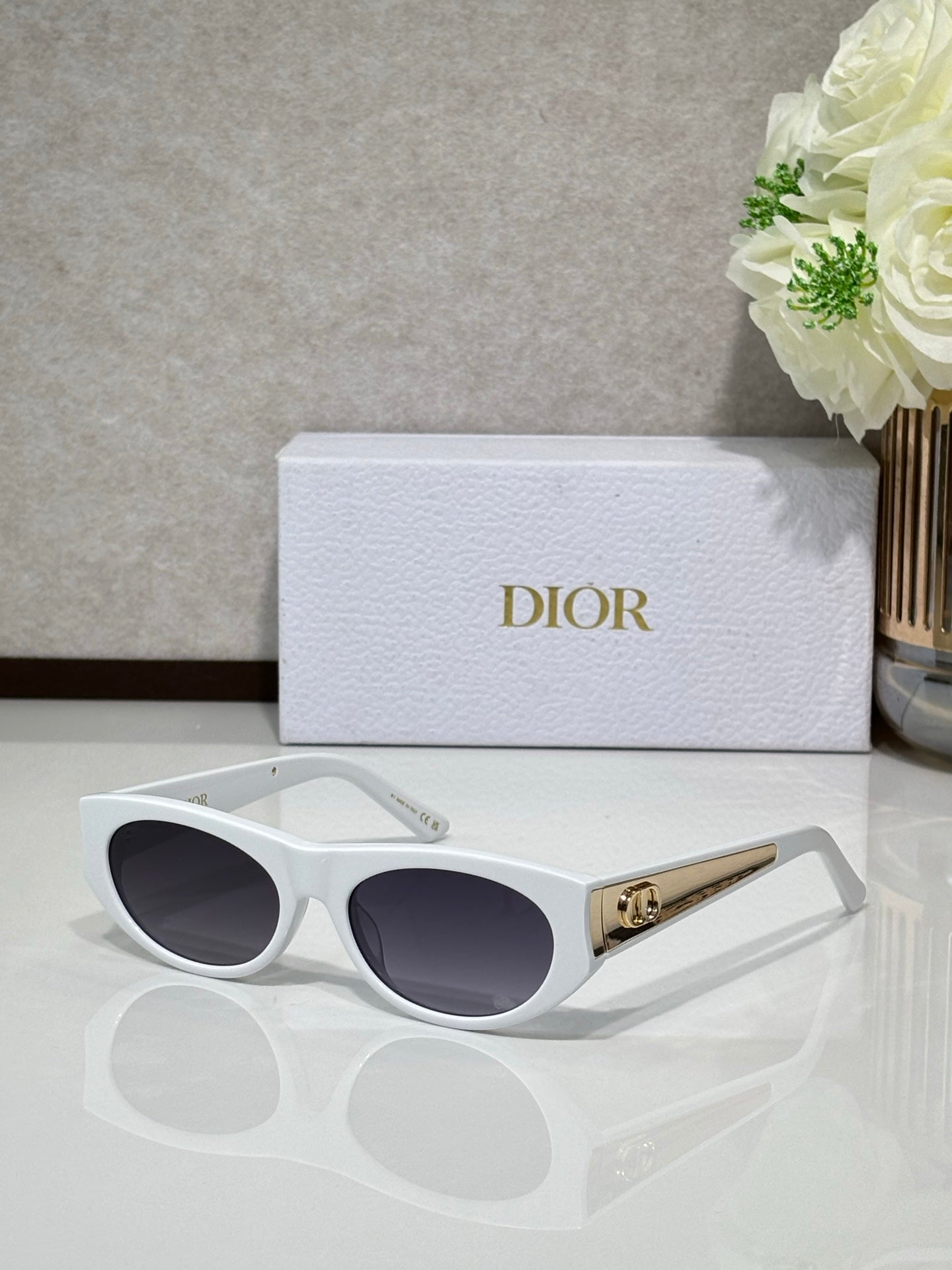 Dior sunglasses with white round frames, dark lenses, and gold logo bar on temple