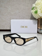 Dior sunglasses with black round frames and neutral lenses, gold logo bar on temple