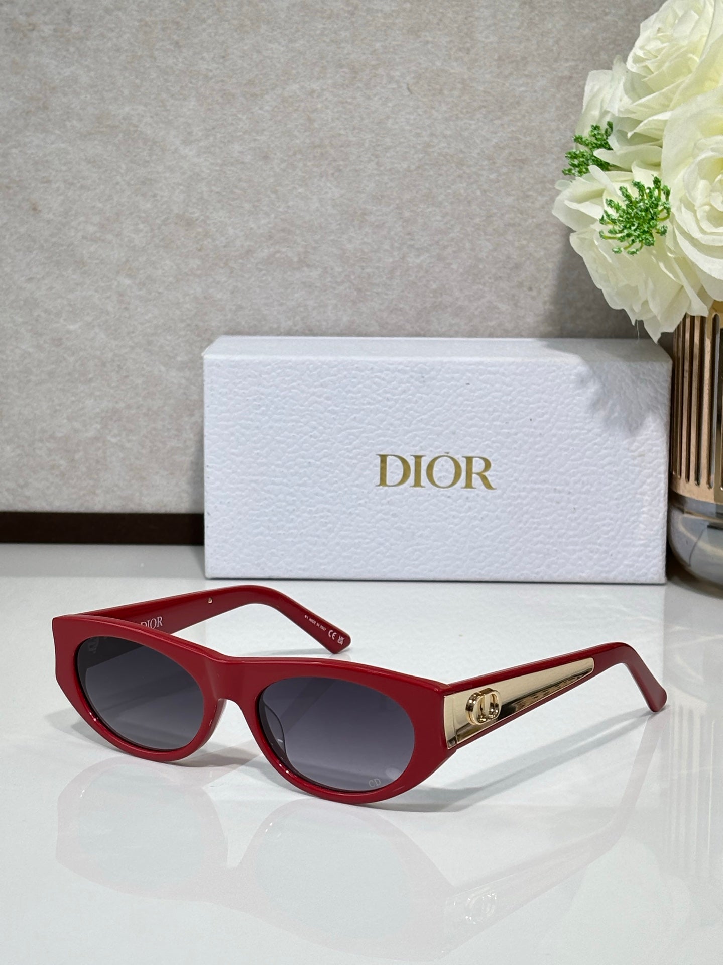 Dior sunglasses with red round frames, dark lenses, and gold logo bar on temple