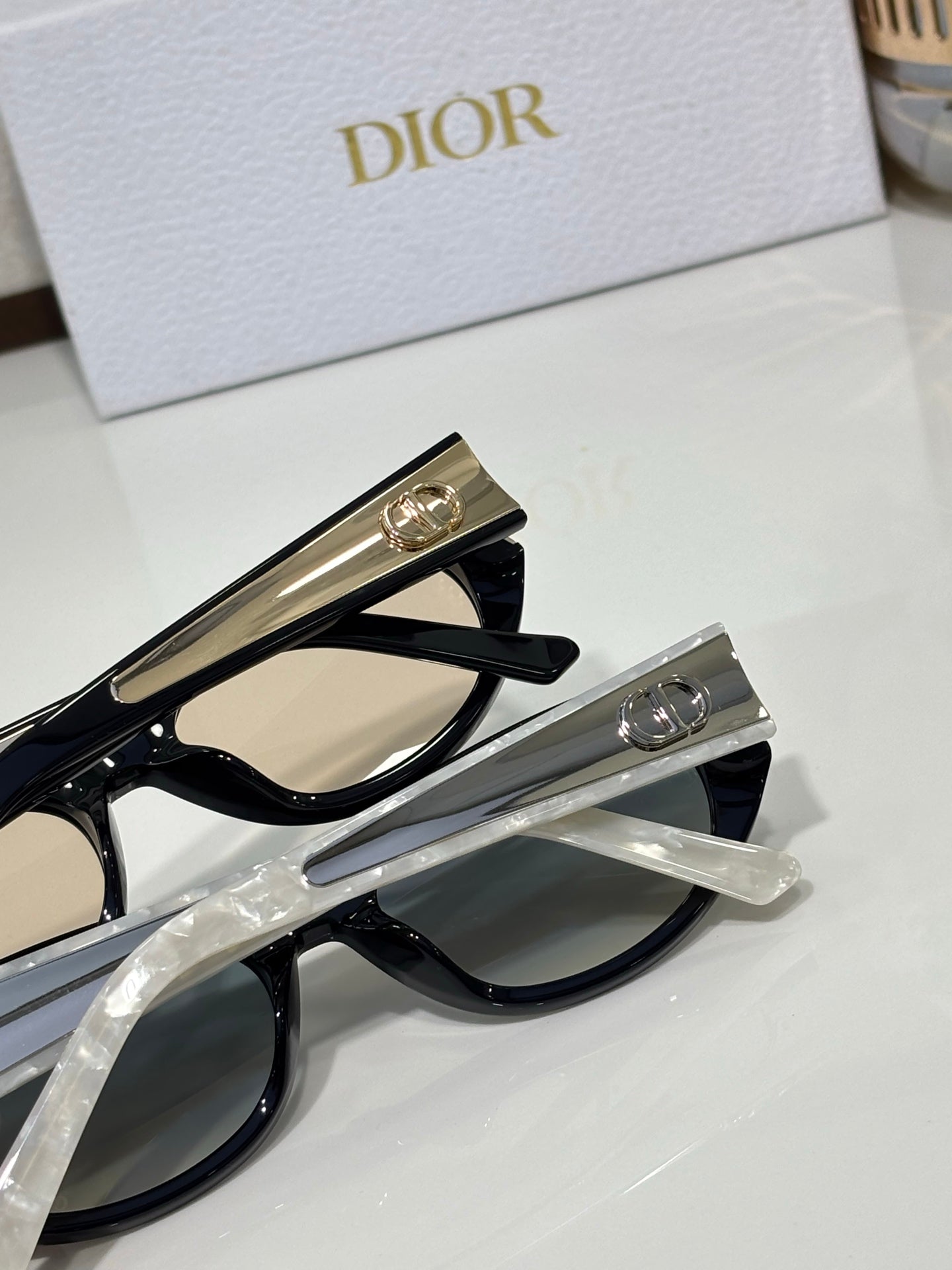 Dior sunglasses close-up with black frames and clear lenses, gold logo temple hardware