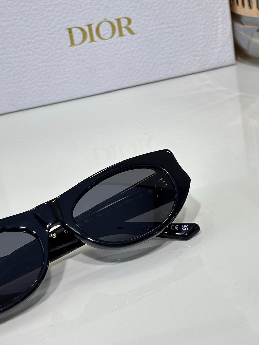 Dior sunglasses close-up with black round frame, dark lens, and logo detail on temple
