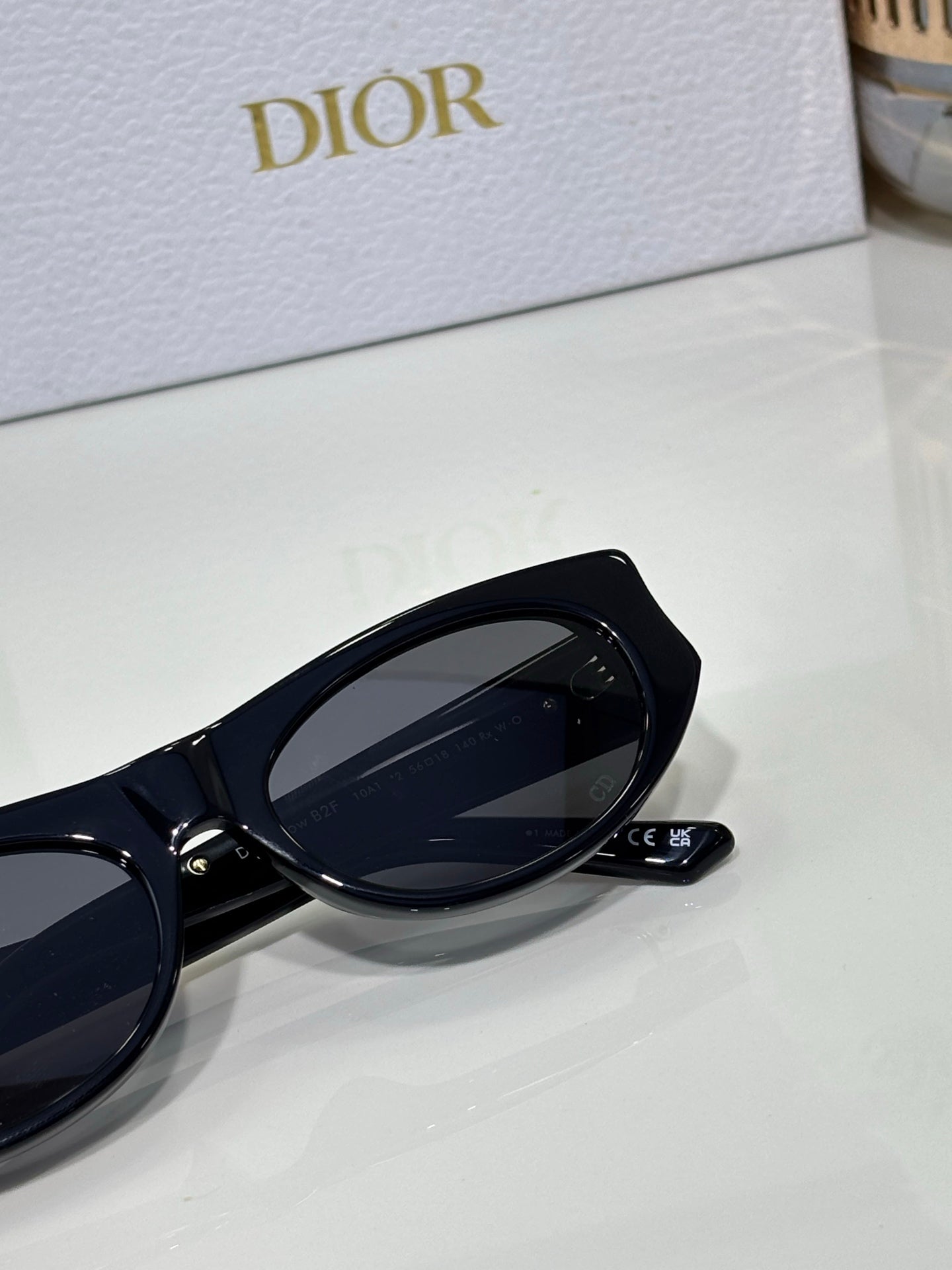 Dior sunglasses close-up with black round frame, dark lens, and logo detail on temple