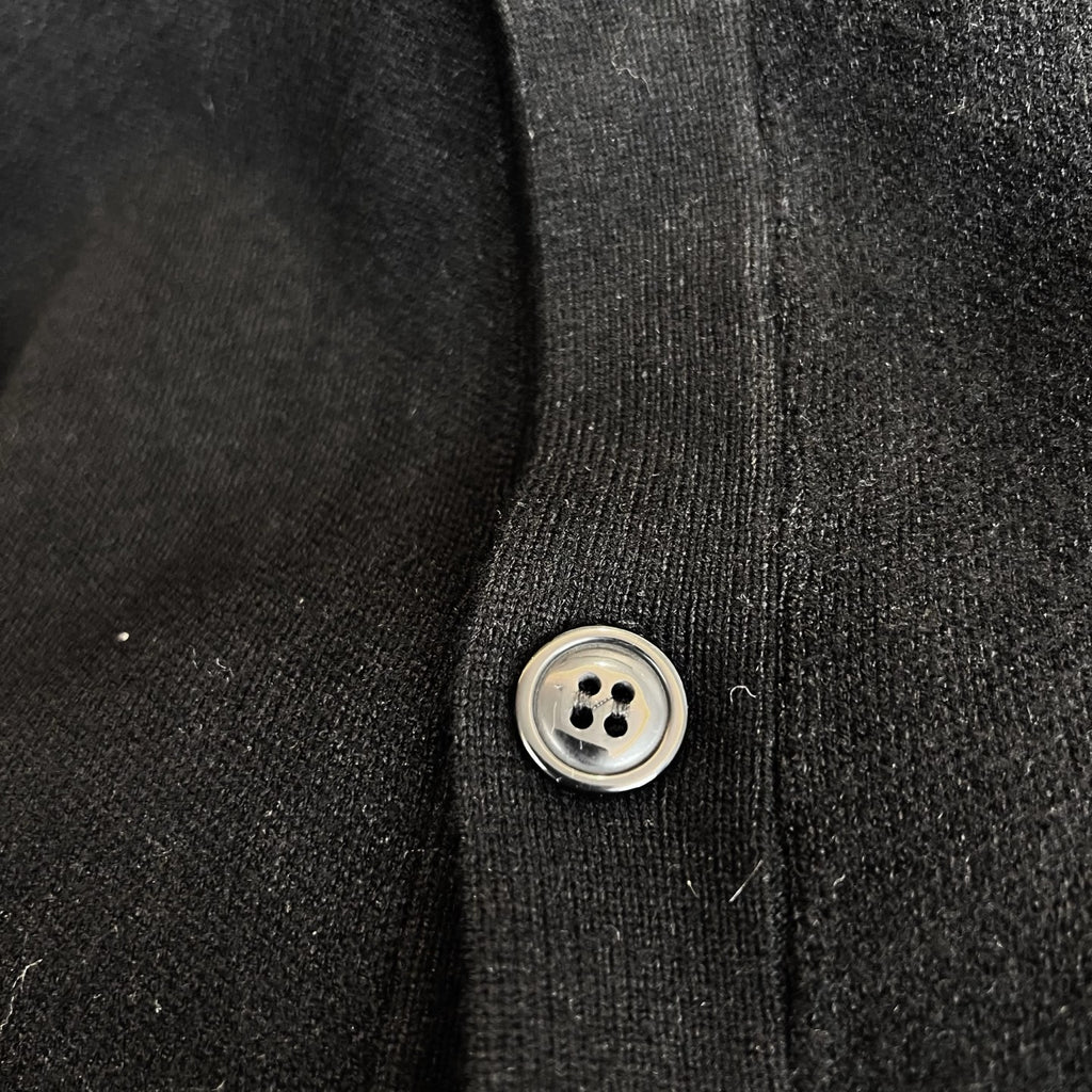 Black knit cardigan button placket with round metal-look button