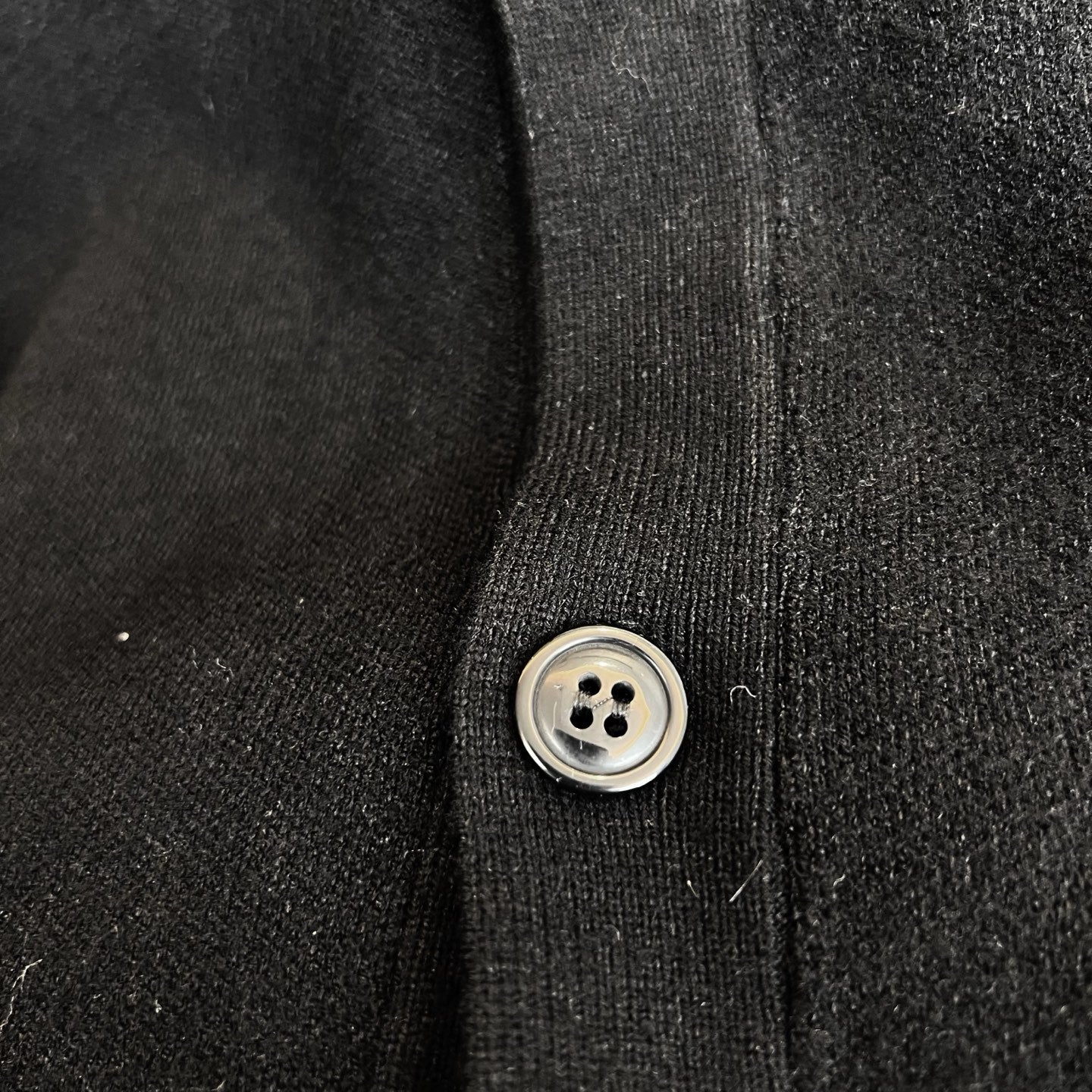 Black knit cardigan button placket with round metal-look button
