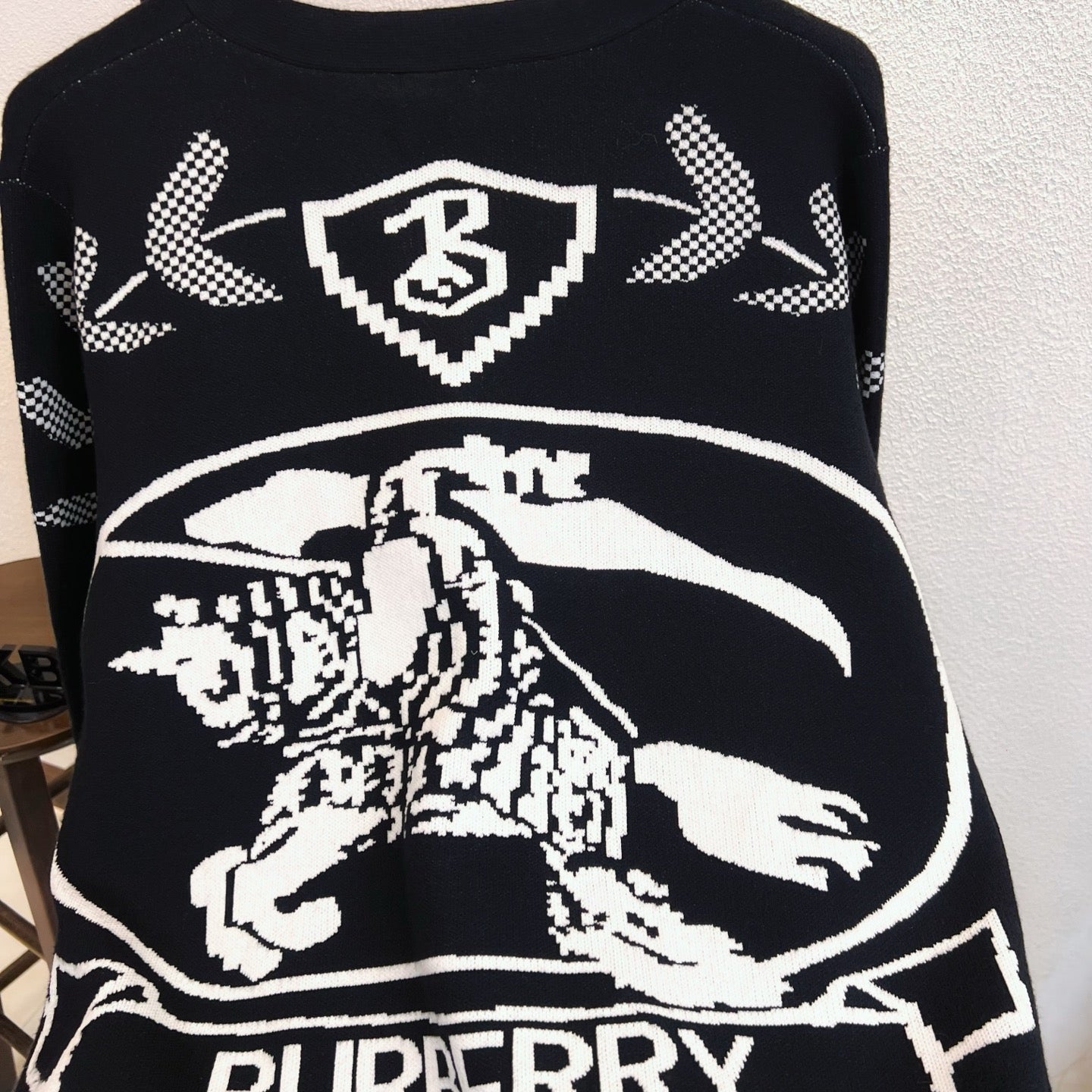 Black sweater showing Burberry crest, horse illustration, and ribbon text