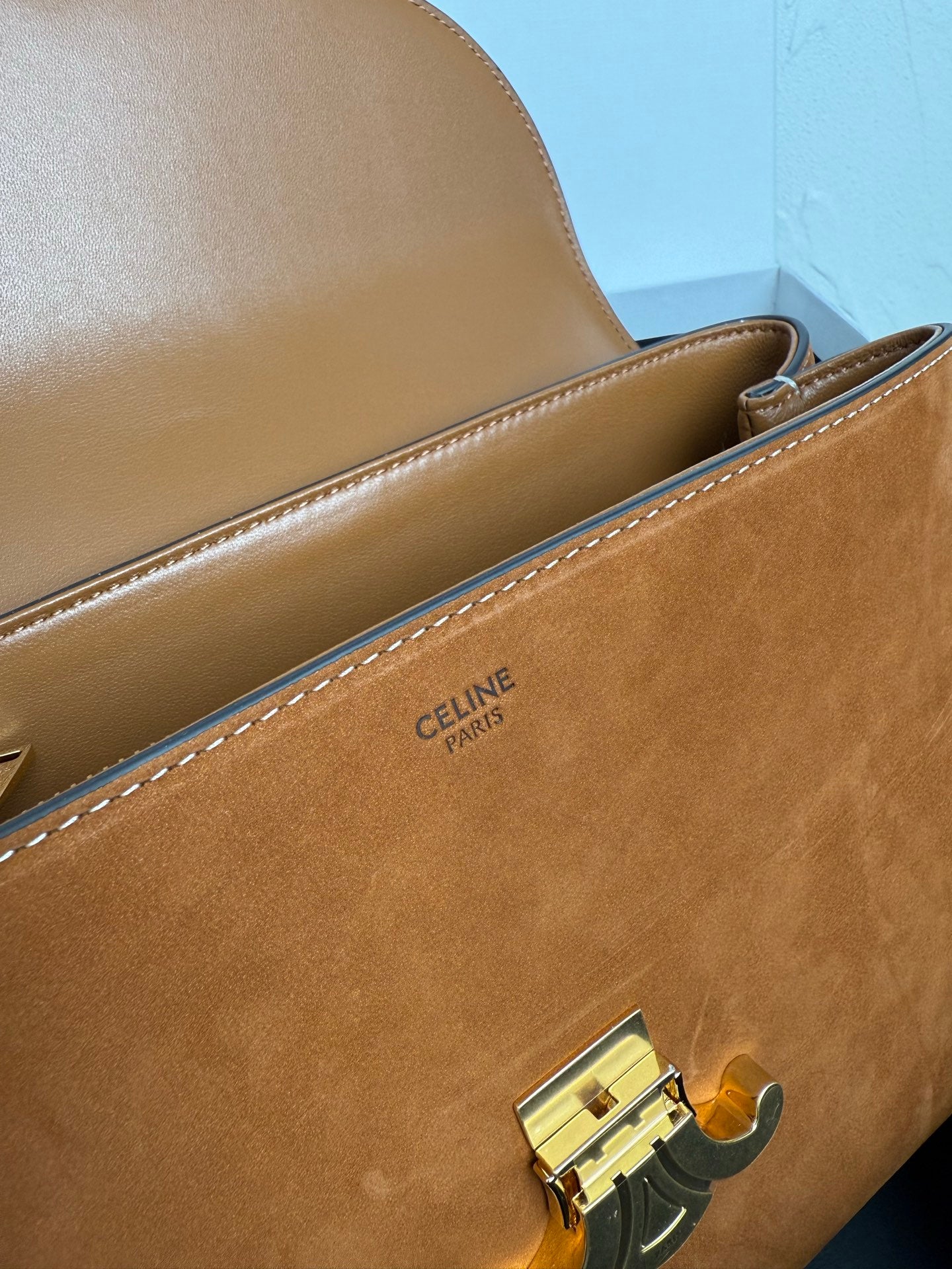 Tan leather bag with gold hardware and stitched designer label on side