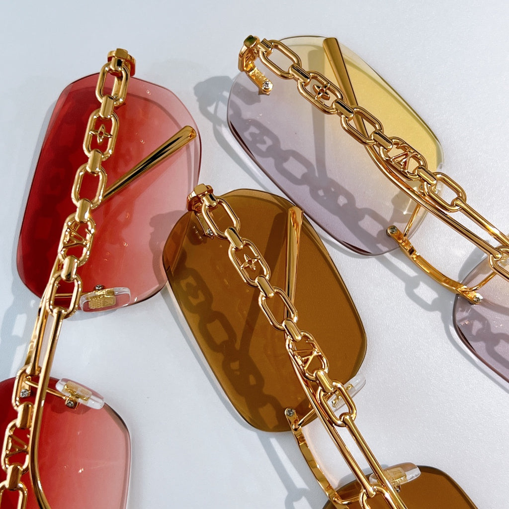 Louis Vuitton sunglasses close-up: red and amber lenses with gold chain frames
