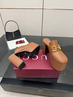 Tan/brown embossed platform mule slides with chunky heel and gold double-buckle hardware