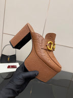 Close-up of tan/brown embossed platform mule with gold double-buckle strap and open side