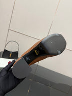 Outsole view of tan/brown platform mule showing dark rubber sole and logo markings