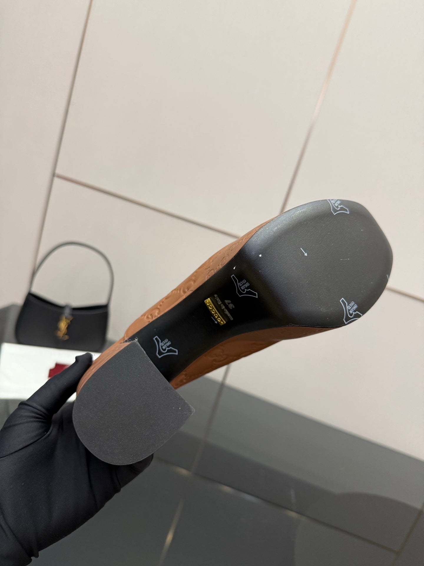 Outsole view of tan/brown platform mule showing dark rubber sole and logo markings