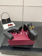 Black Gucci platform mules with gold buckle strap and textured leather pattern