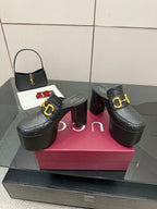 Pair of black Gucci platform mules with gold buckle and textured logo pattern
