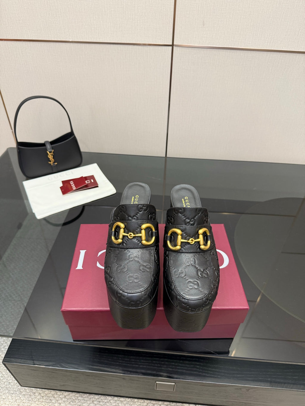 Black Gucci mule clogs with gold buckle detail and chunky platform sole