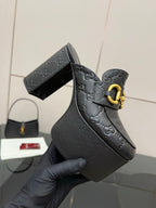 Close-up of black Gucci platform mule with gold buckle strap and logo embossing