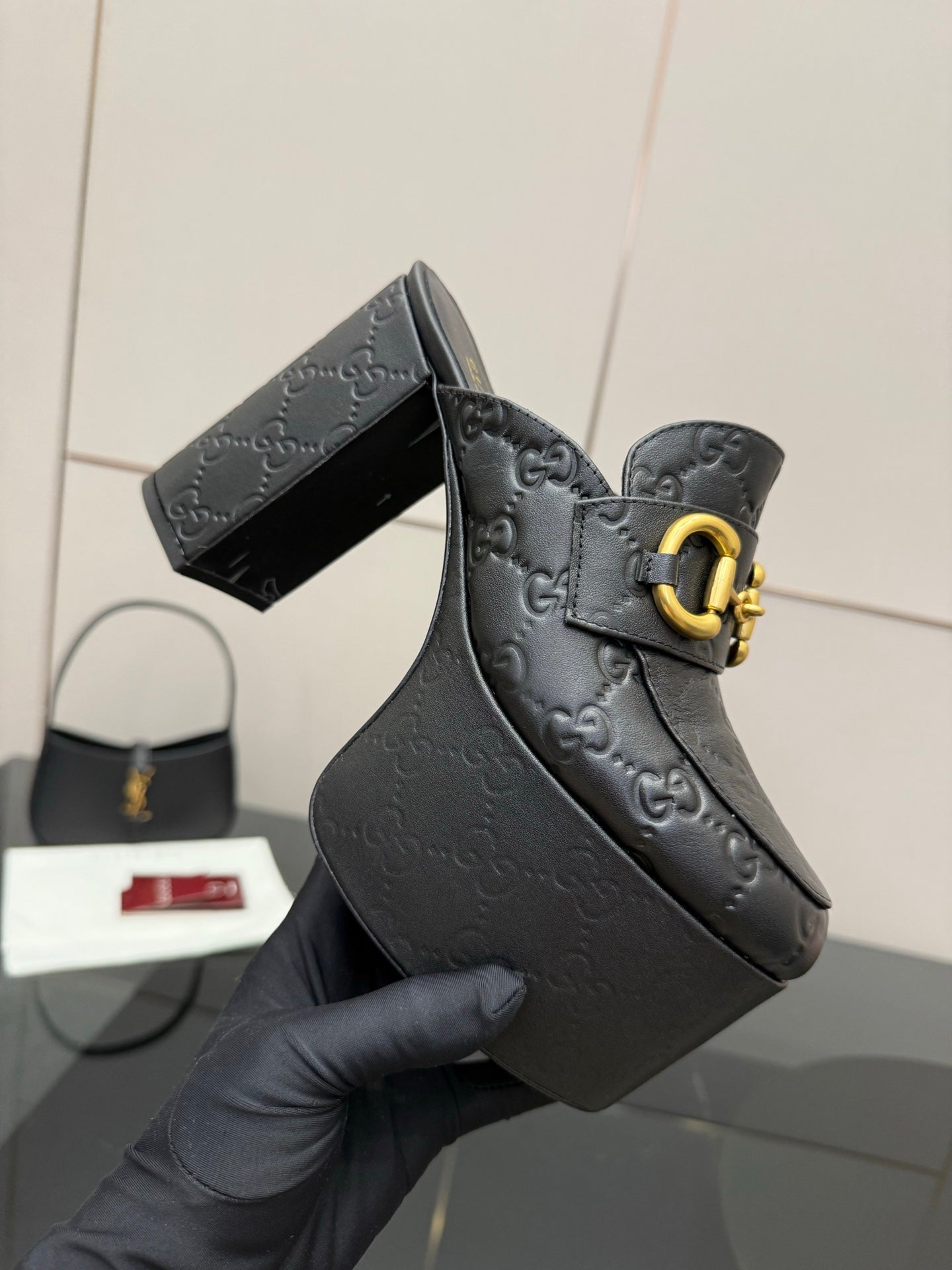 Close-up of black Gucci platform mule with gold buckle strap and logo embossing