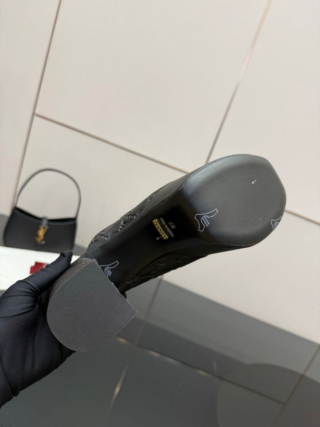 Bottom view of black Gucci platform mule showing outsole and logo pattern
