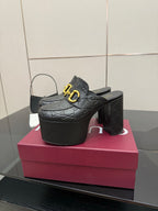 Black Gucci mule clogs with gold buckle, textured logo pattern, chunky platform