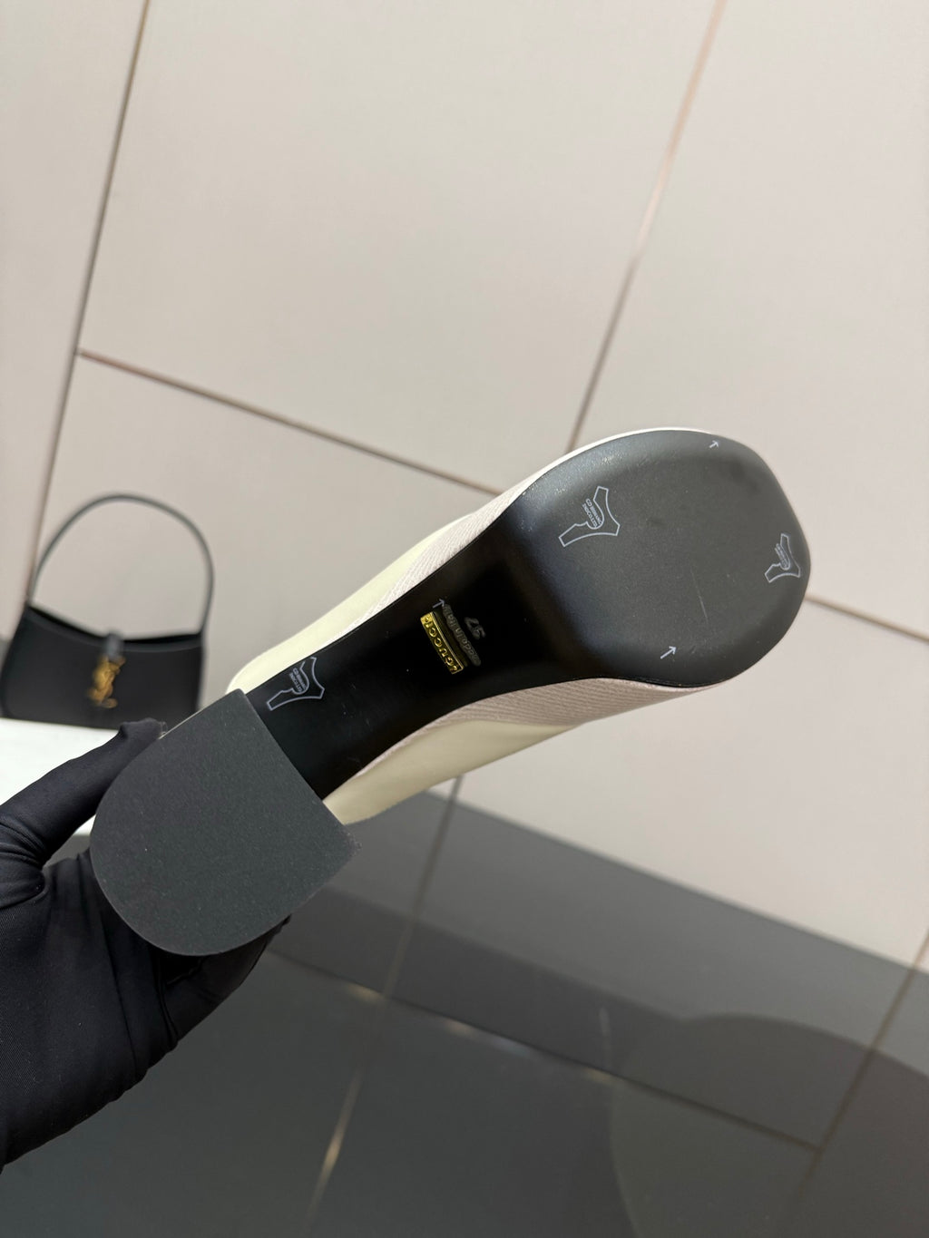 Gucci ladies off-white mule clog outsole view with molded logo text on the rubber sole
