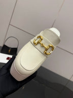 Gucci ladies off-white mule clog close-up with gold logo bit hardware and slip-on strap