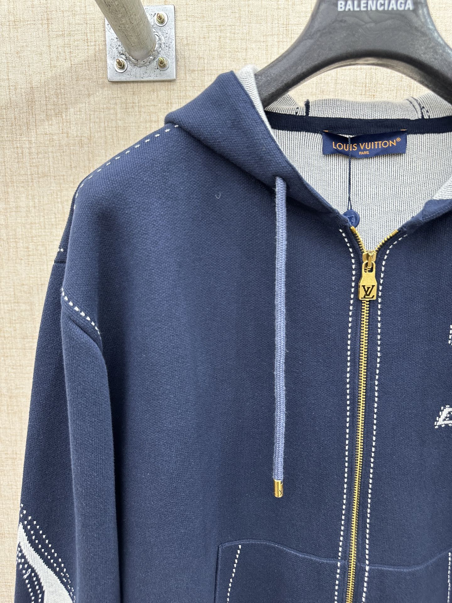 Navy hooded zip jacket with drawstrings, front pocket, and logo on chest