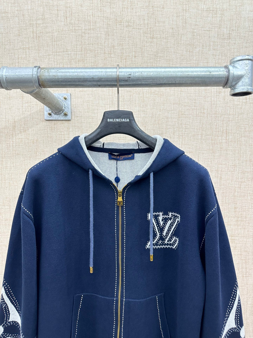 Navy zip-up hoodie with hood, drawstrings, and chest logo; graphic sleeve accents
