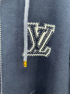 Close-up of navy hoodie chest logo patch with yellow zipper pull and drawstring