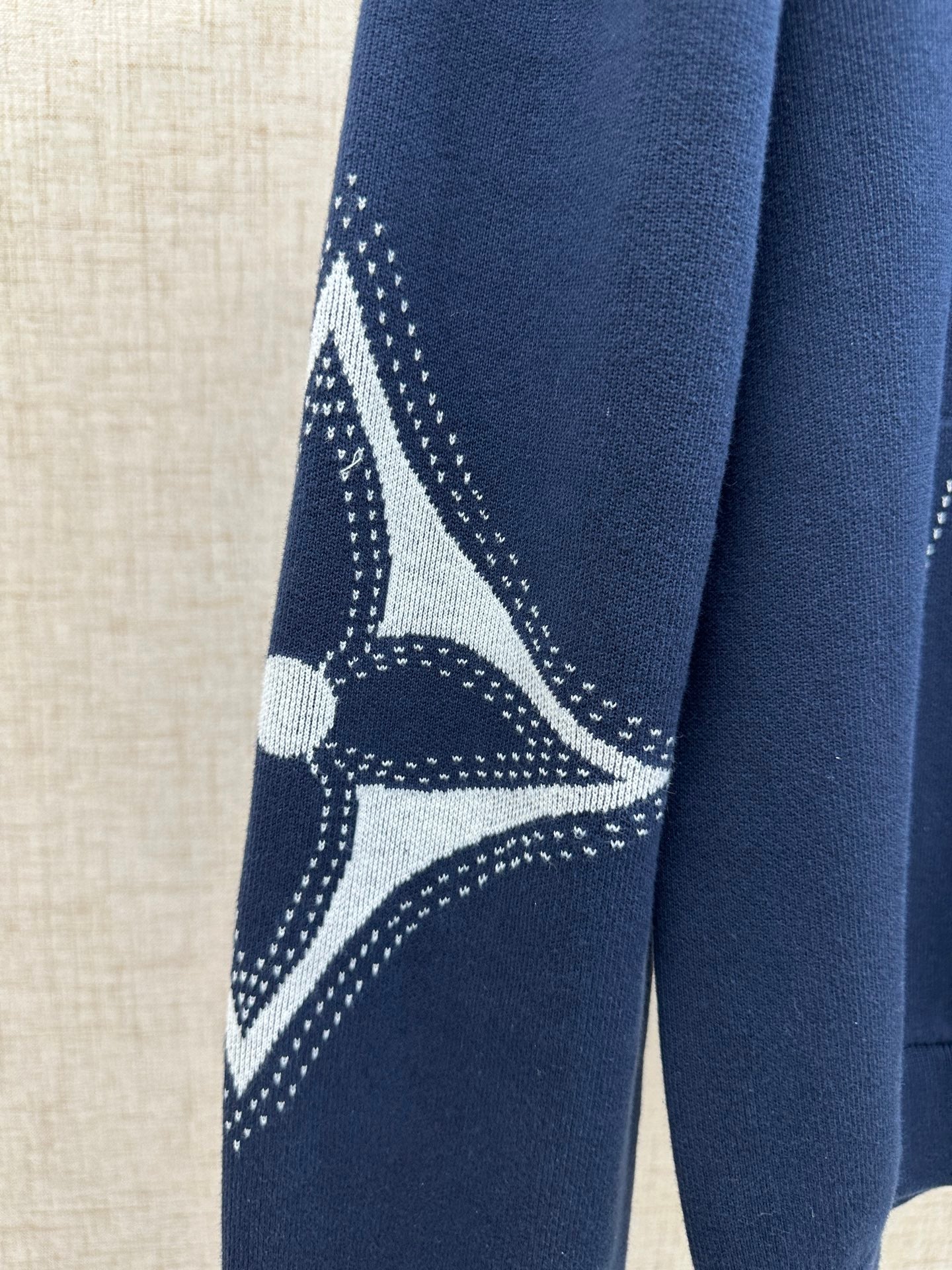 Navy hoodie sleeve with white emblem graphic and dotted lines