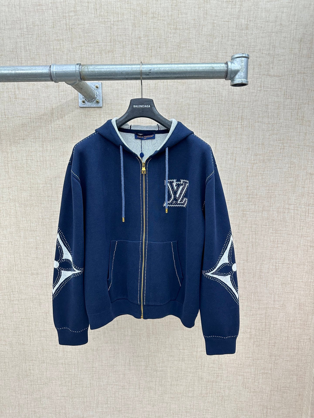 Navy zip-up hoodie with hood, drawstrings, front pockets, and logo chest detail