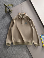 Beige long-sleeve polo with button placket, collar, and chest logo patch