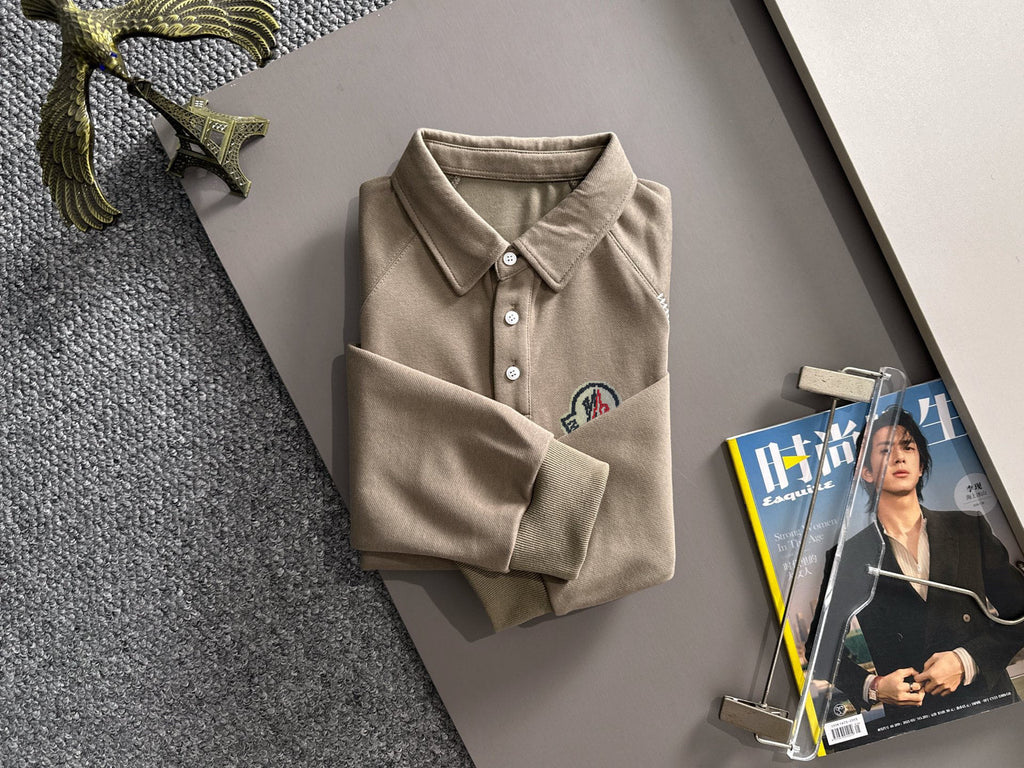 Beige long-sleeve polo folded with collar, buttons, and chest logo patch
