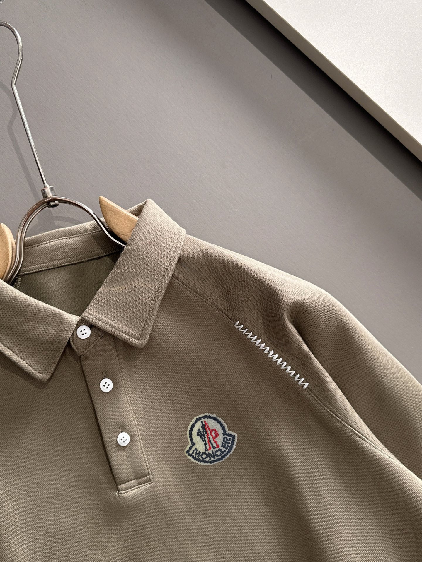 Beige long-sleeve polo with pointed collar, button placket, and embroidered chest crest