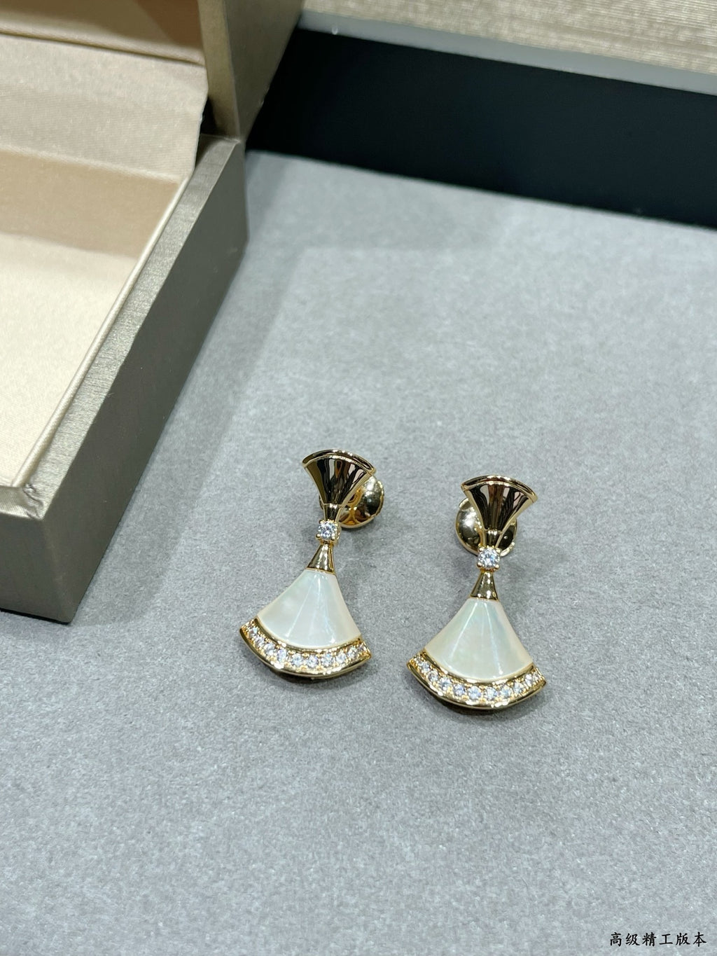 Pair of gold-tone earrings with white fan-style drops and rhinestone trim