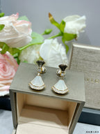 Gold-tone dangle earrings with white fan-style drops and rhinestone border