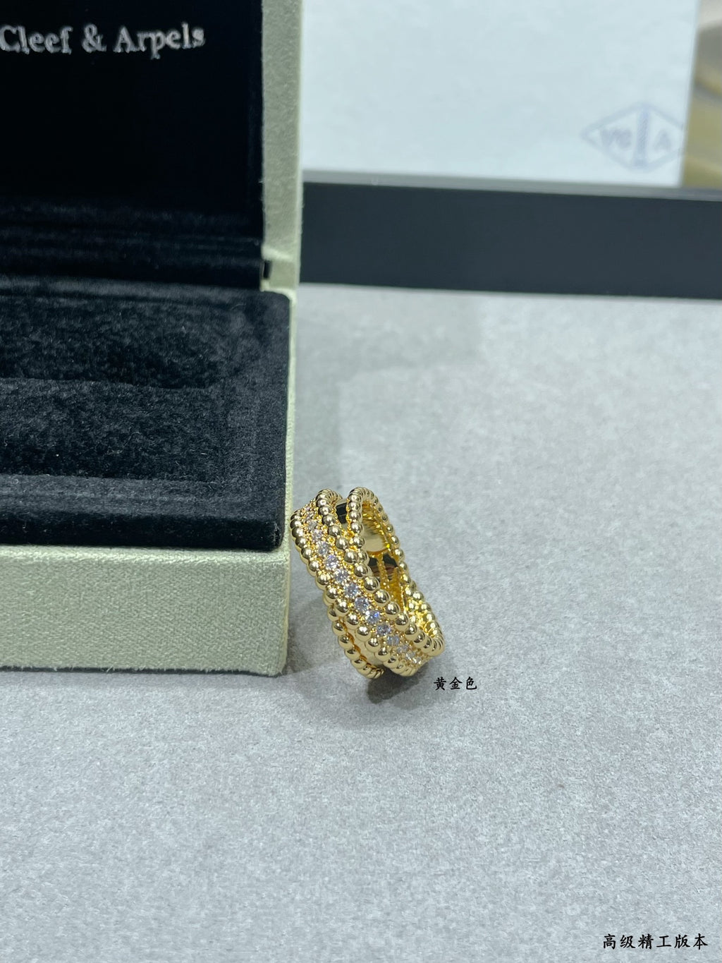 Gold-tone pavé ring with curved stacked stones on display beside jewelry box