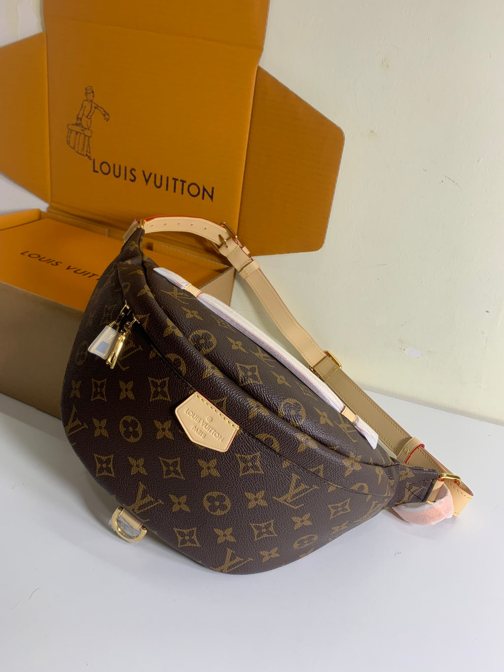 Louis Vuitton monogram crossbody bag with long strap and front plaque, brown, angled view.
