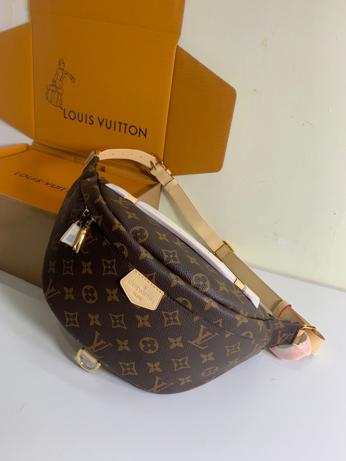 Louis Vuitton monogram crossbody bag with long strap and front plaque, brown, angled view.