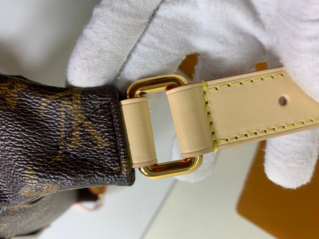 Louis Vuitton monogram bag strap attachment with gold D-ring and beige trim, close-up.