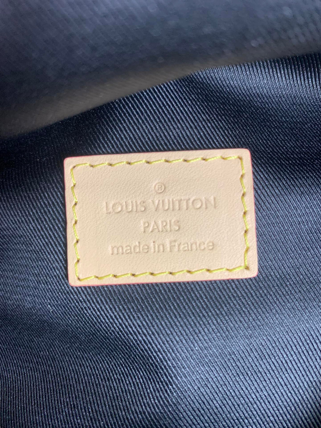 Louis Vuitton PARIS made in France label on dark fabric, stitched leather patch