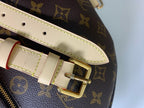 Louis Vuitton monogram bag strap buckle with beige trim and gold clasp, close-up.