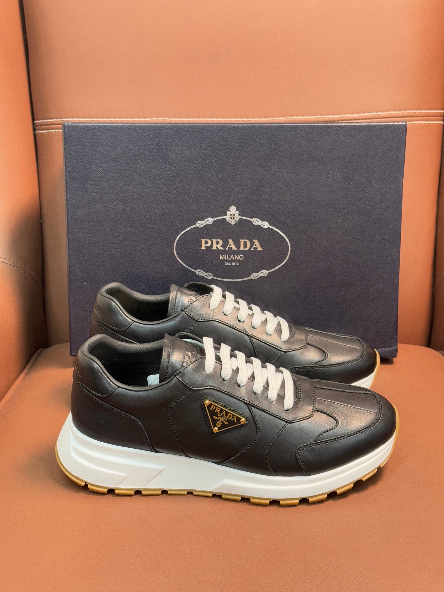 PRADA low-top sneakers, dark leather with white laces, chunky white sole with yellow edge