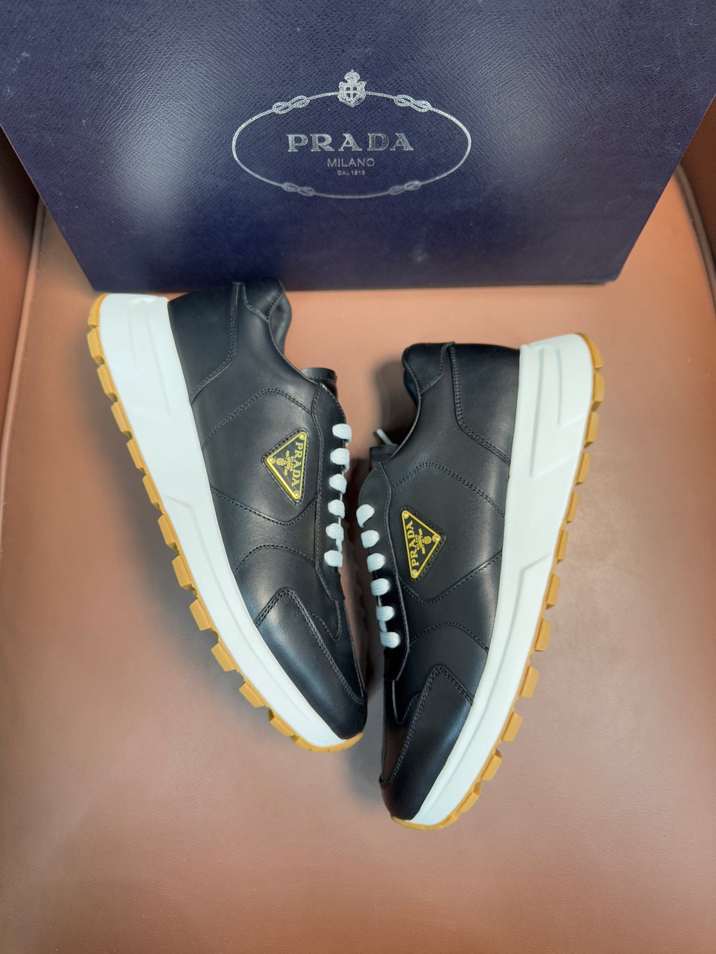 PRADA low-top sneakers, dark leather with white laces, off-white panels, yellow sole