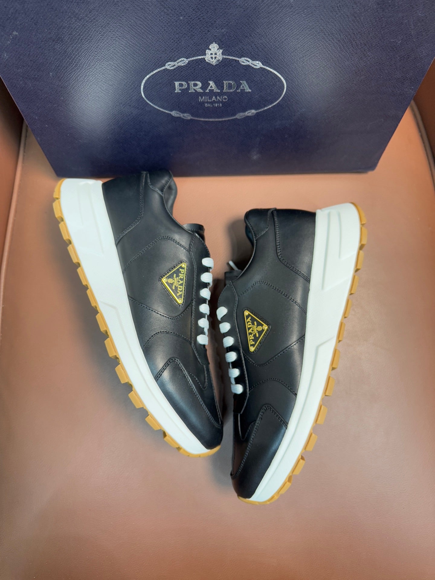 PRADA low-top sneakers, dark leather with white laces, off-white panels, yellow sole