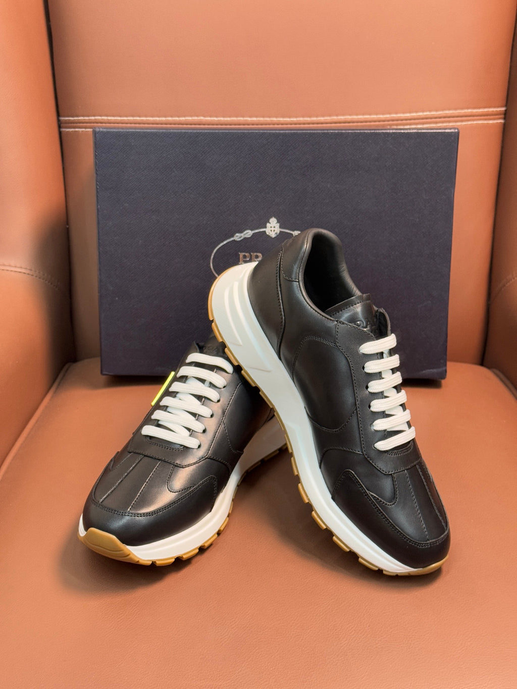 PRADA low-top sneakers, dark leather with white laces and off-white sole with yellow edge