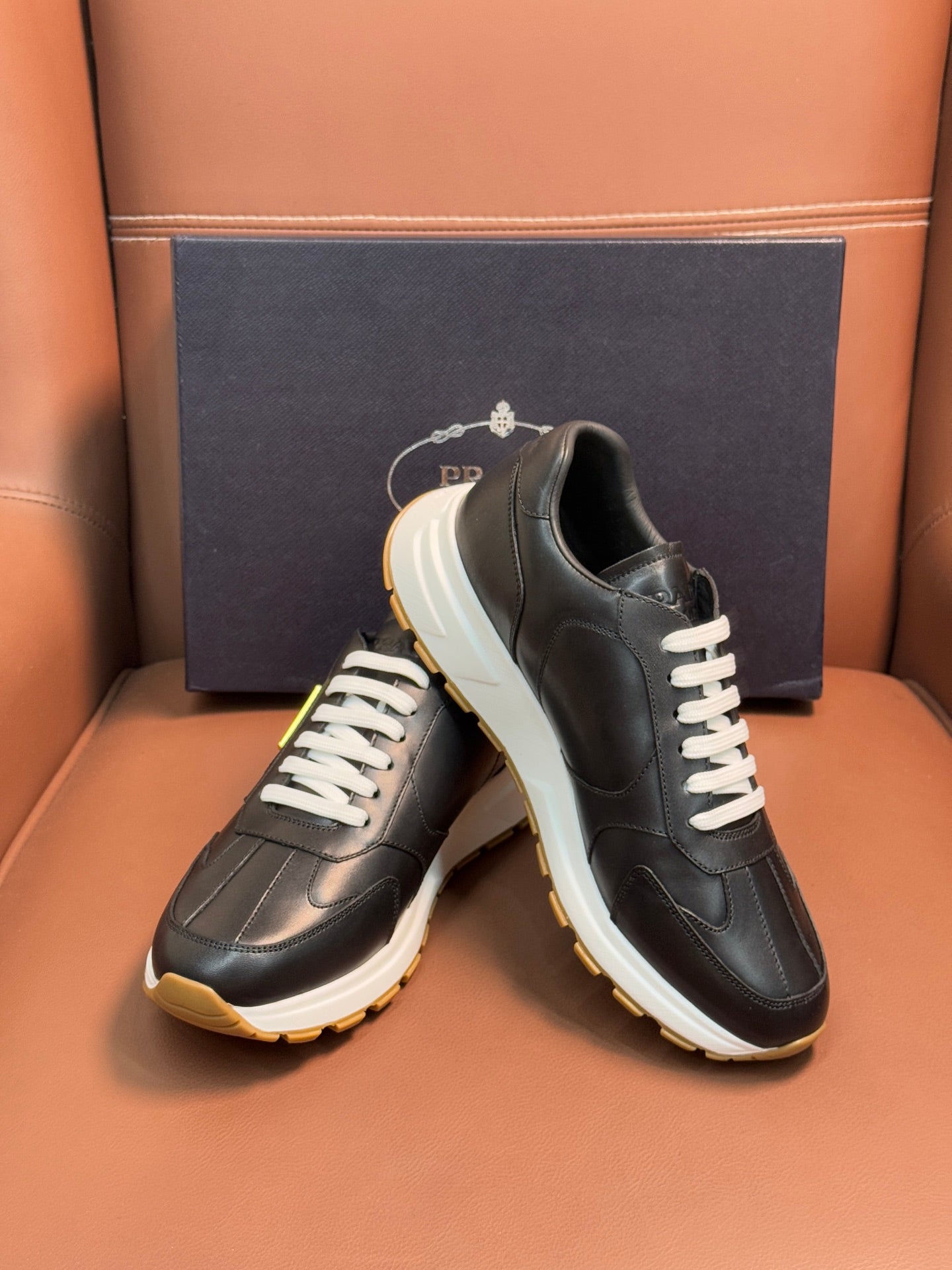 PRADA low-top sneakers, dark leather with white laces and off-white sole with yellow edge