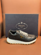 PRADA low-top sneaker, dark leather with white laces and chunky white sole, yellow tread