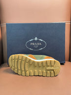 Unisex Prada sneakers outsole view, tan and green upper with textured rubber tread.