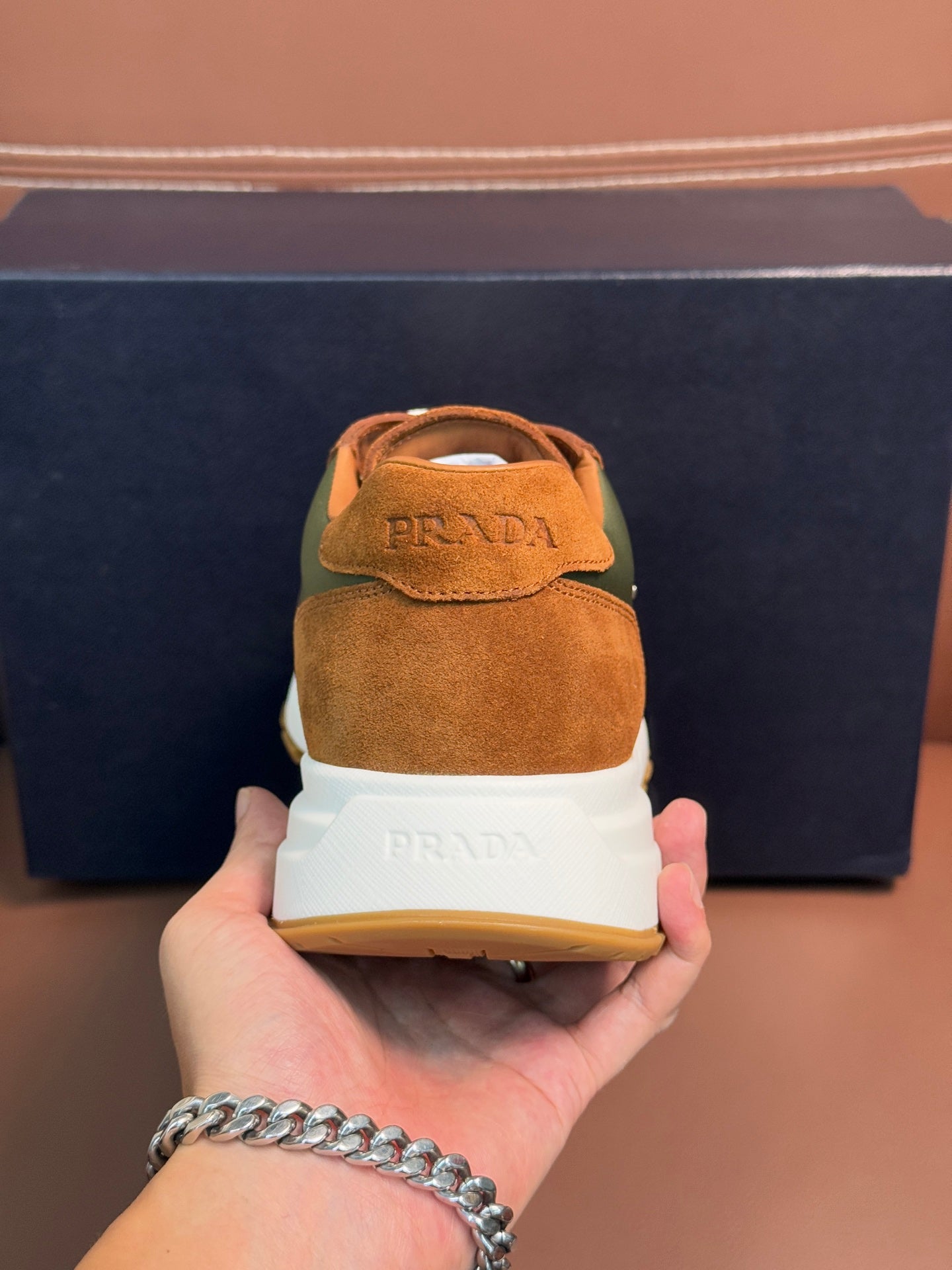 Unisex Prada sneaker heel in tan suede with green side panel, white sole edge and logo.