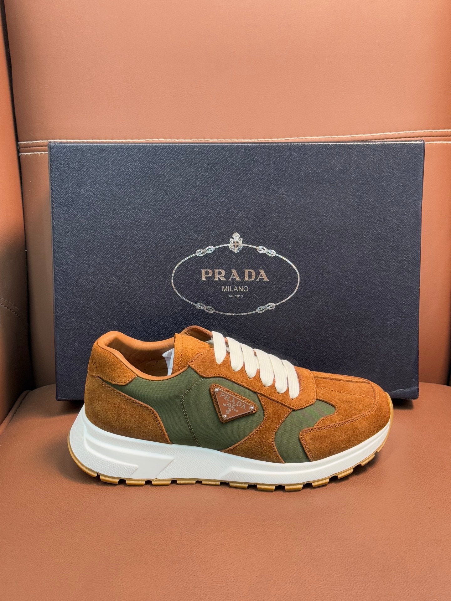 Unisex Prada low-top sneakers, tan suede with green panels, white laces and sole.